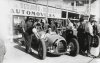 Fotografía del piloto Archille Varzi sobre su bólido Auto-Union conversando con su equipo