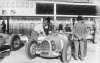 Fotografía del piloto Archille Varzi sobre su bólido Auto-Union conversando con su equipo