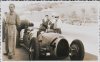 Fotografía del piloto Archille Varzi posando junto al automóvil Auto-Union de Bernard Rosemayer, que esta siendo puesto apunto por los mecánicos